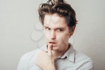 Closeup portrait of a young handsome man biting his finger nails with a craving for something or anxious. Negative human emotion facial expression feeling