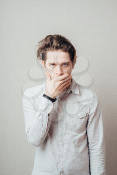 Young man covering his mouth with hands 