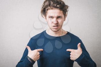 A man shows his hands on himself. On a gray background.