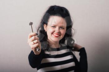 Woman hand holding keys. Gray background