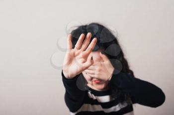 Woman showing a stop hand and closes her eyes. Gray background.