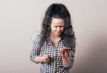 Woman reading sad message on the phone. On a gray background.