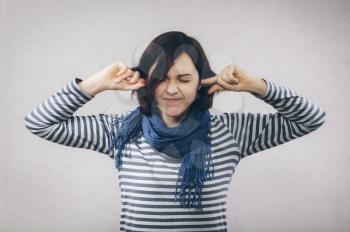 Young woman covering her ears over white background