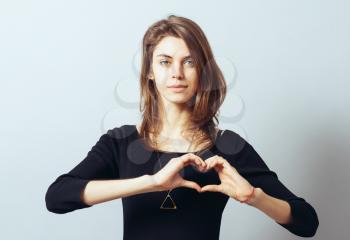 beautiful young woman making a heart gesture with her fingers