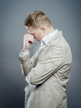 A young tired man close-up in a suit on a gray background, fall asleep. The guy wants to sleep. Gesture. Photos