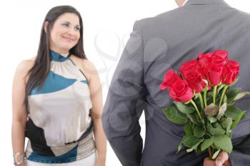 man hiding bunch of red roses behind his back to surprise his girlfriend
