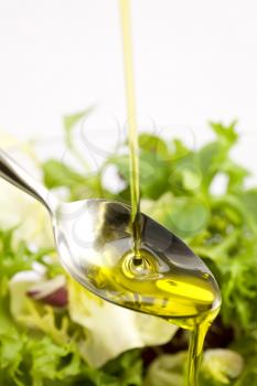 Pouring olive oil in the salad over a spoon