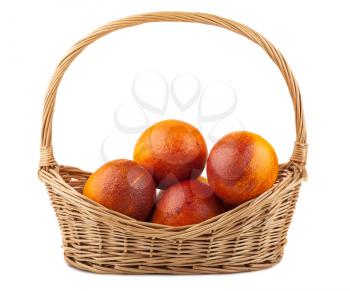 Blood red oranges in wicker basket isolated on white background