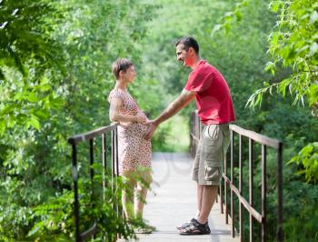Royalty Free Photo of a Husband and His Pregnant Wife on a Bridge