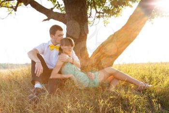 Young couple lying under the tree with backlight
