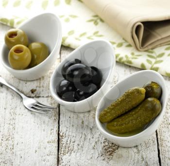 Pickles,Green And Black Olives On A Wooden Board