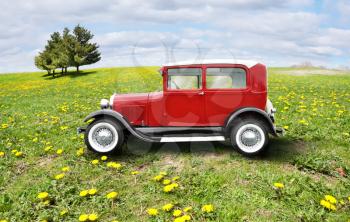 red retro car on a green field