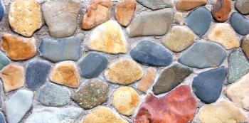 Stone wall of the house from different color of stones in a laying