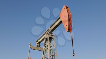 Operating oil and gas well in oil field, profiled against the blue sky.