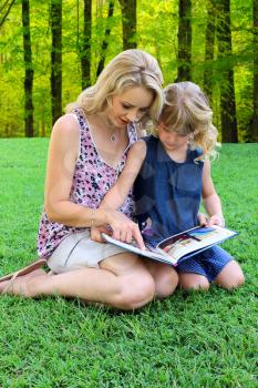 Lovely Mom and daughter Reading Book Outdoors