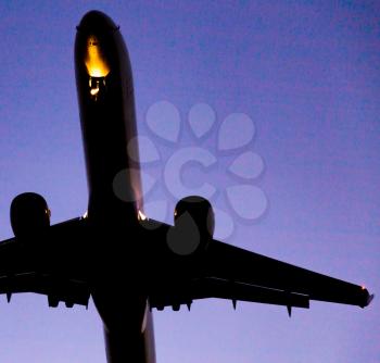 Silhouette of a landing aircraft at sunset .