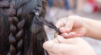 the stylist weaves the female braids on the head .