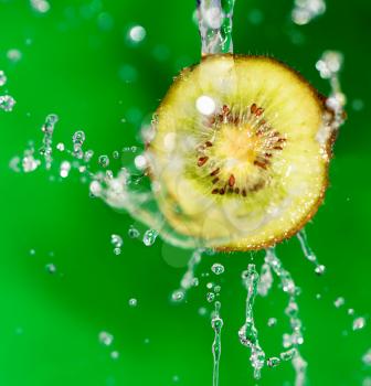 kiwi fruit in a spray of water on a green background