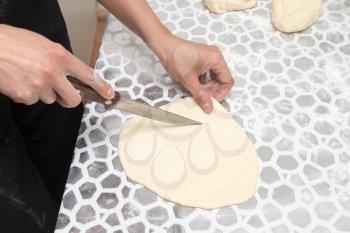 cutting the dough with a knife in the kitchen