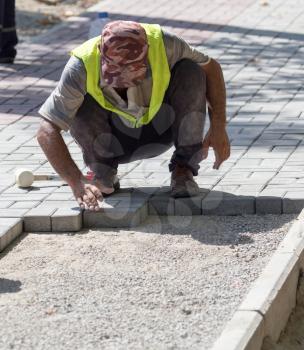 Worker puts sidewalk tile on the road