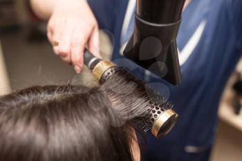 Styling female hair dryer in the beauty salon