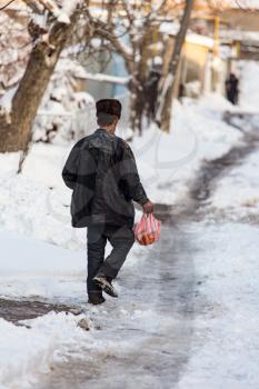 Homeless man is walking on the road in winter .