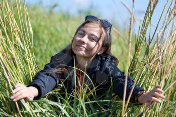 Woman in sunglasses looks through the grass with ears.