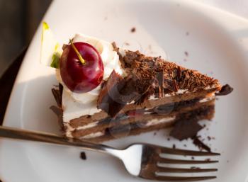 chocolate cake with cherries on a white plate with a fork
