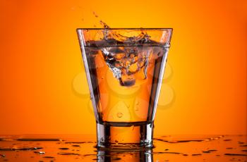 Ice in a glass of water. Orange background