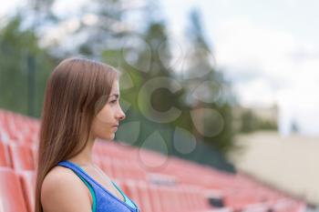 Portrait of a young brunette woman in profile at the stadium.