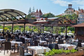 Chic outdoor restaurant on the background of the castle and the blue sky.