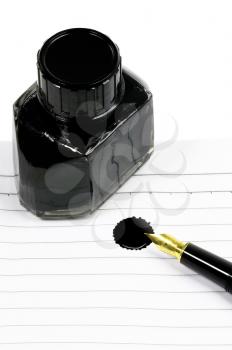 classic black fountain pen on open notebook with ink bottle with stain on page