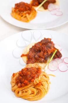 traditional Italian spaghetti pasta with pork ribbs sauce served on polenta bed