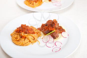 traditional Italian spaghetti pasta with pork ribbs sauce served on polenta bed
