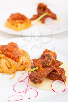 traditional Italian spaghetti pasta with pork ribs sauce served on polenta bed