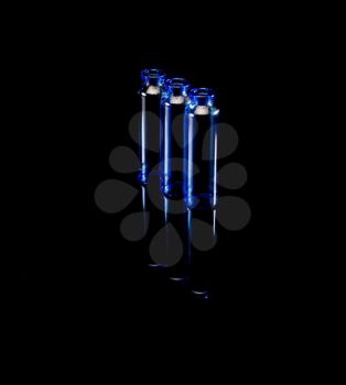 blue glass vials over black background backlit