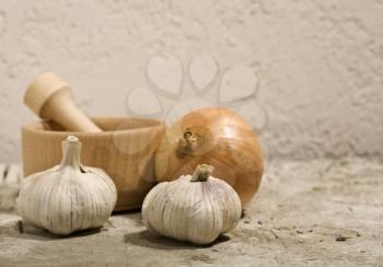 Royalty Free Photo of Garlic and Onion Beside a Mortar and Pestle