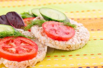Puffed rice crackers sandwiches with vegetables on tablecloth.