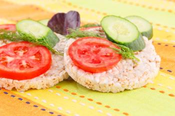 Puffed rice crackers sandwiches with vegetables on tablecloth.