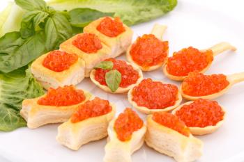 Red caviar in pastries and lettuce on plate.