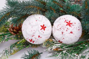 Christmas white balls, cones and fir-tree branch on gray background.