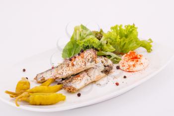 Fish, peppers, lettuce  and cream on white plate.
