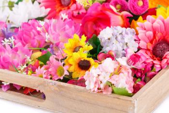 Colorful fabric flowers in wooden box, closeup picture.