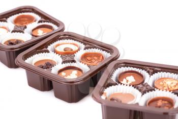Assortment of chocolate in plastic boxes on white background.