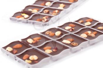 Chocolate with assortment nuts in plastic boxes on white background.
