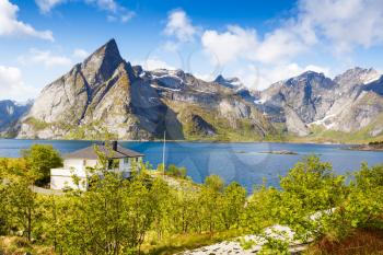 Landscape with high rocky mountains, white house  and fjord in Hamnoya, Norway.
