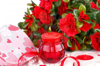Red flowers, candles and gift box close up picture.