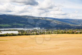 Landscape with wheat field, river and mountains in Norway.