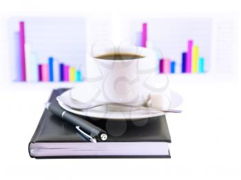 Coffee cup, standing on the personal organizer, on a back background-financial diagrams . Isolated