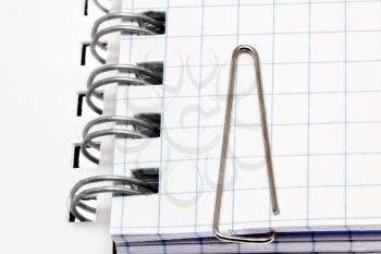 Paper clip  on notebook pages. Isolated over white